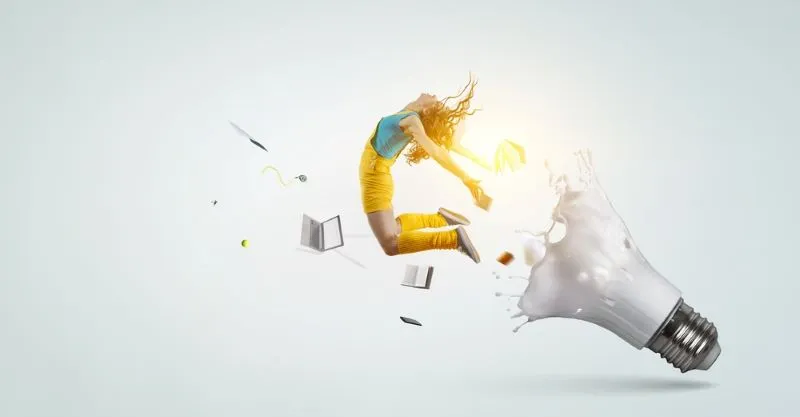 Imagen conceptual de una mujer saliendo de una bombilla de luz, con libros, computador, hojas