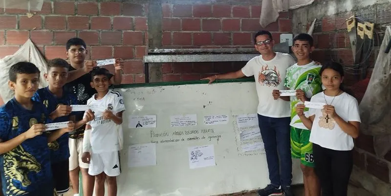 Grupo de niños y un docente, de los equipos participantes, junto a un tablero