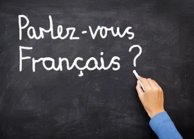 Foto de una mano que escribe con tiza en un tablero la frase "Parlez vous Français?"