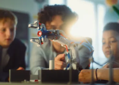 Niños trabajando cerca a una mano robotica
